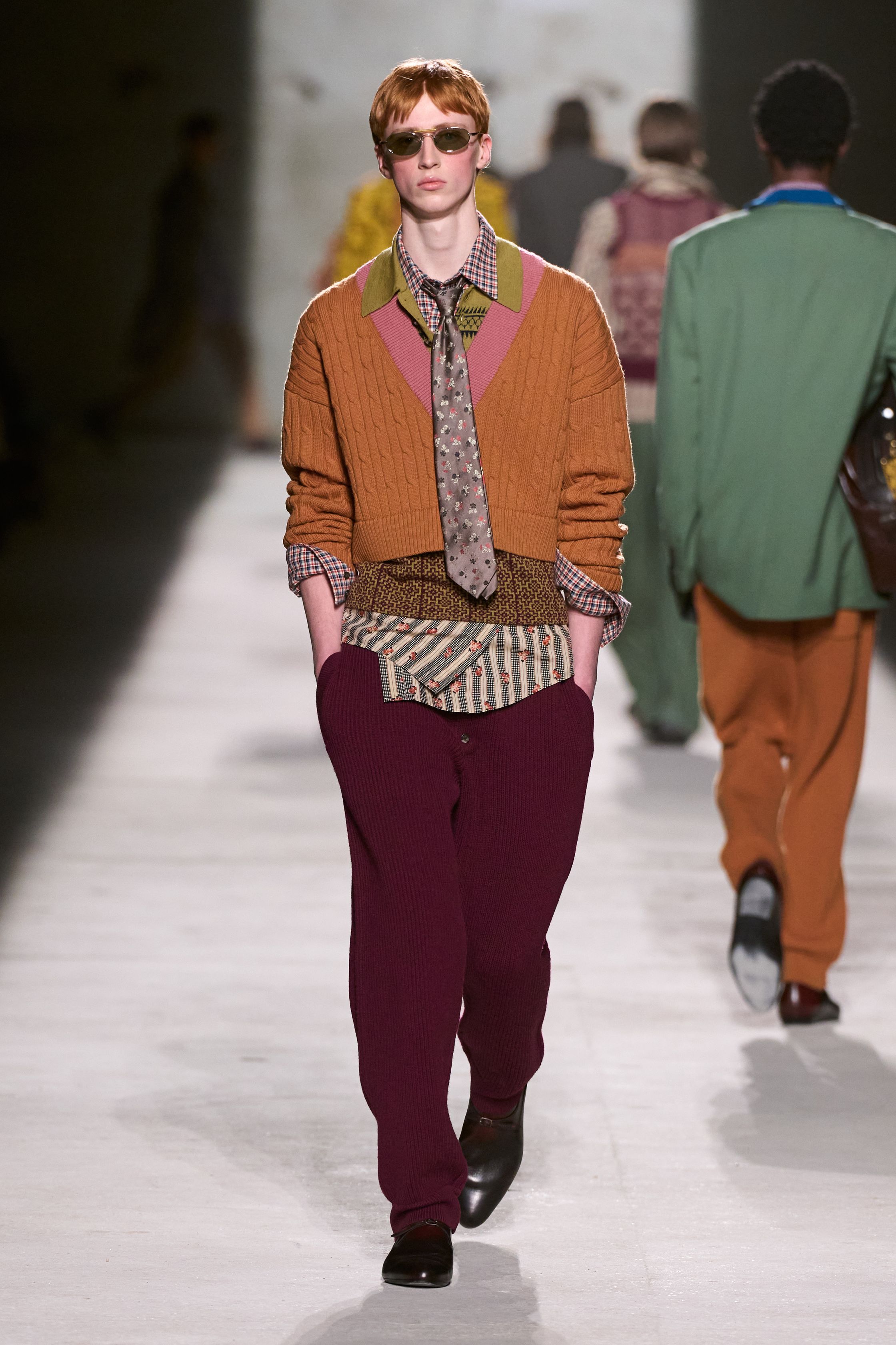Dries Van Noten 2026秋冬以高度成熟的综合色彩与织物语言，继续书写其标志性的“文化层叠美学”。民族图案针织、拼接围巾、军装轮廓与优雅大衣在行走中形成复杂而克制的视觉节奏，色彩看似丰富却始终维持理性秩序。这是一种属于思想型穿着者的浪漫，不依赖情绪爆发，而通过织物、比例与色块的精密组合，构建出安静却极具深度的男性诗意-顽石频道趋势研究